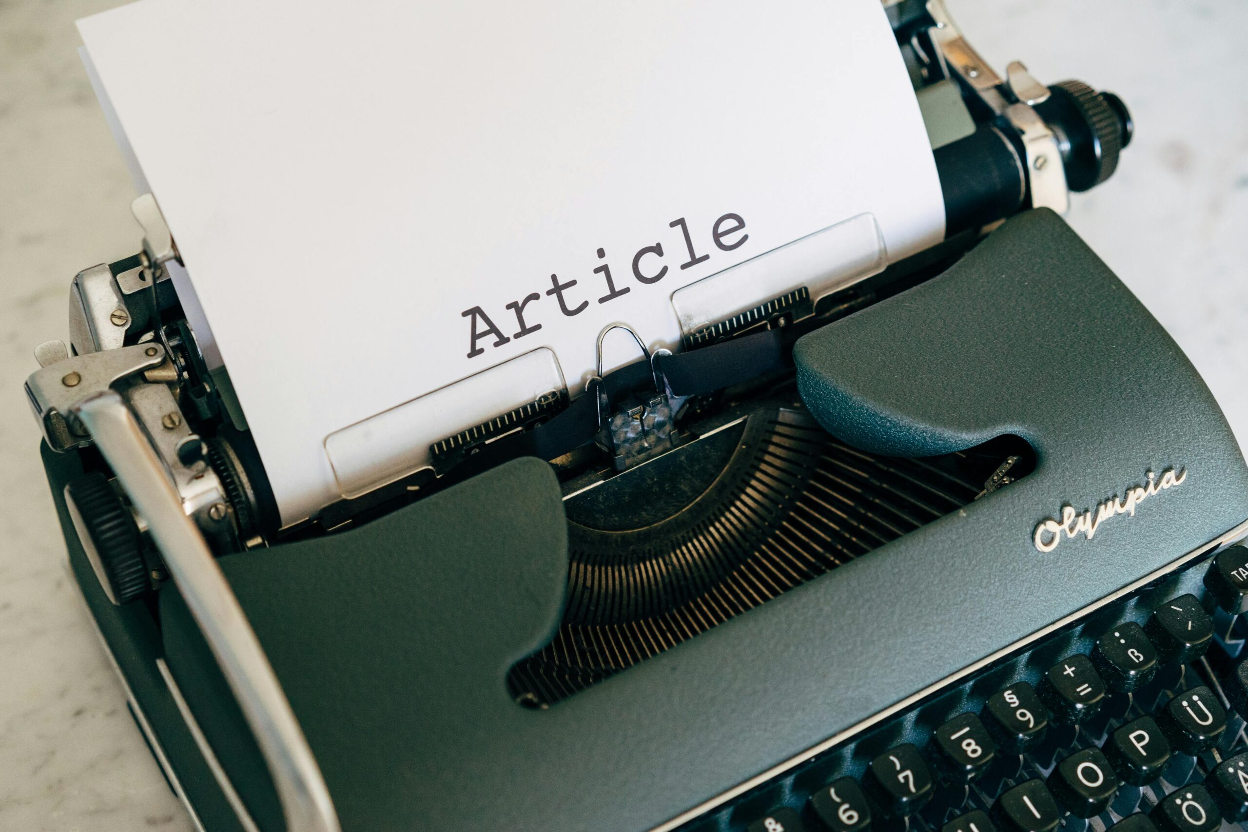 Top view of a vintage Olympia typewriter with paper titled 'Article'.
